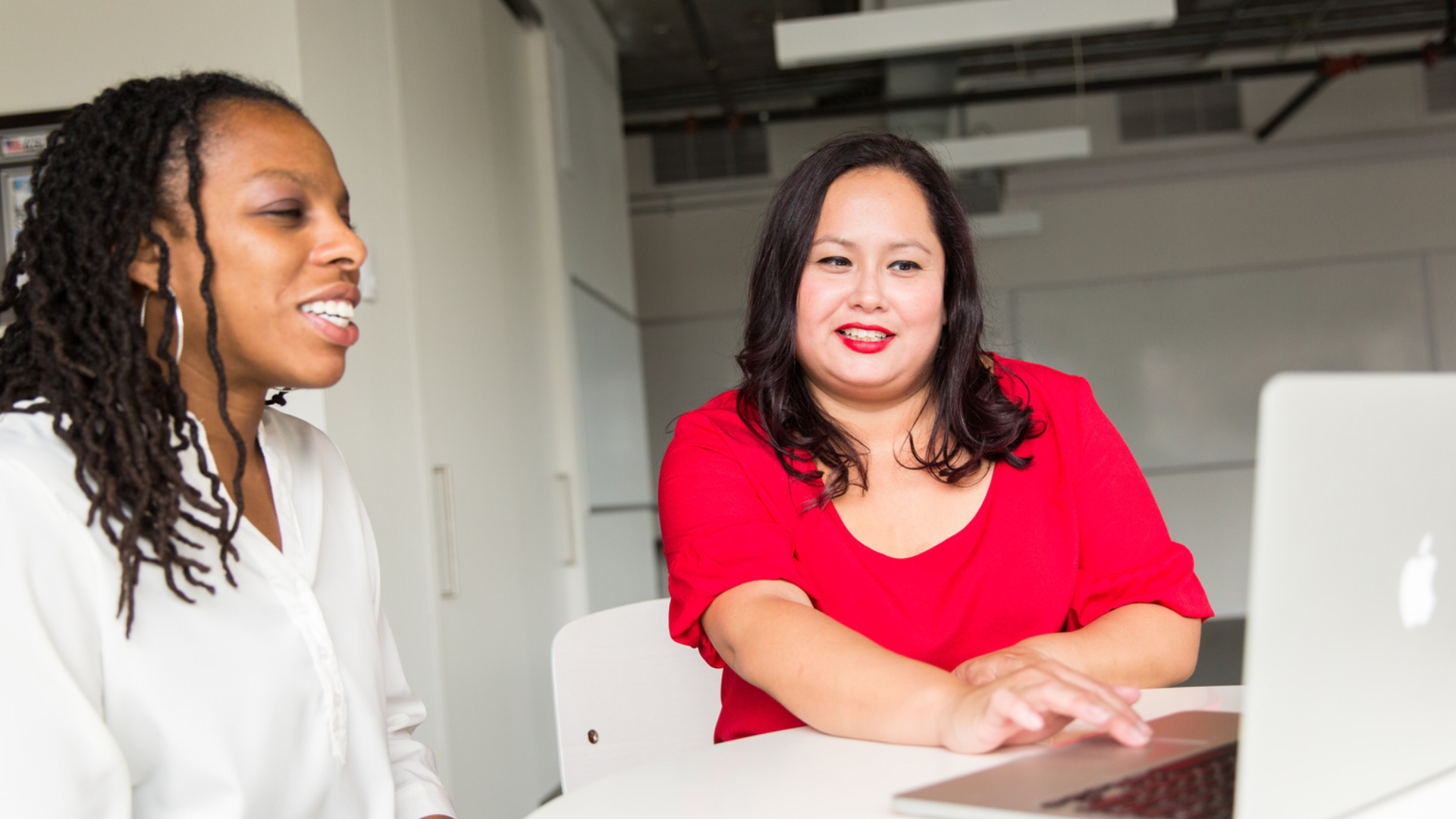 Two women discussing work while looking at a laptop